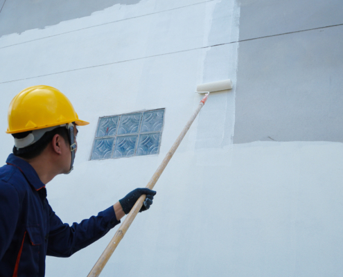 Man In A Hard Hat Painting Exterior Wall