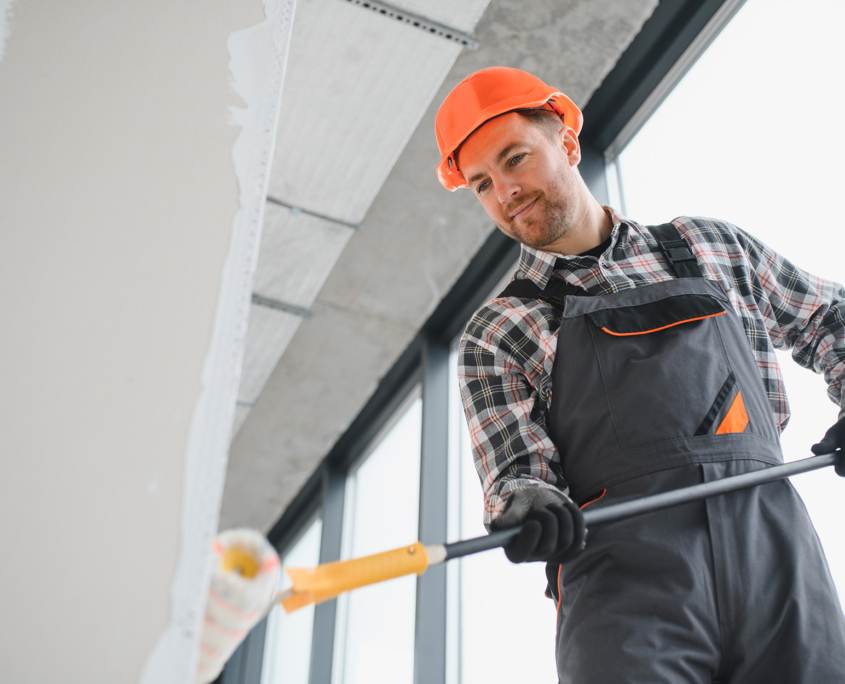 Smiling Man Painting The Wall Of A Building